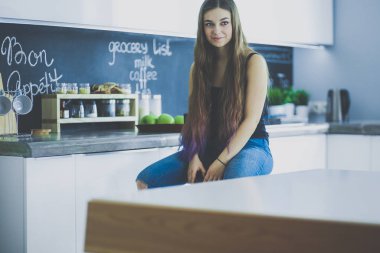 Mutfakta masada oturan genç kadın.