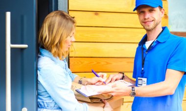 Mavi üniformalı gülümseyen kurye servis konseptine paket kutusu teslim eden teslimatçı. Mavi üniformalı gülümseyen teslimatçı.