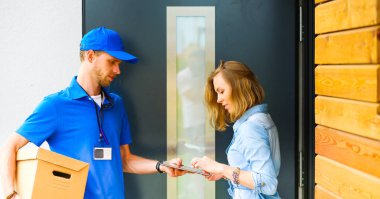 Mavi üniformalı gülümseyen kurye servis konseptine paket kutusu teslim eden teslimatçı. Mavi üniformalı gülümseyen teslimatçı.