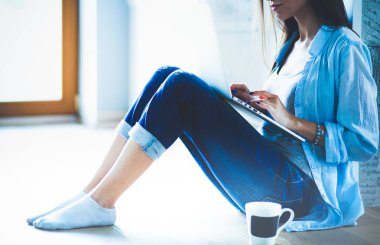 Dizüstü bilgisayar ile yerdeki genç güzel kadın evde oturuyor. Genç güzel kadın.