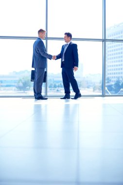 İki başarılı iş adamının el sıkışırken tam boy görüntüsü.