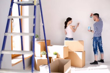 Yeni evin içini boyayan mutlu, genç bir çiftin portresi. Genç çift