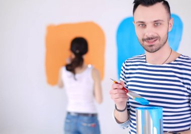Yeni evin içini boyayan mutlu, genç bir çiftin portresi. Genç çift