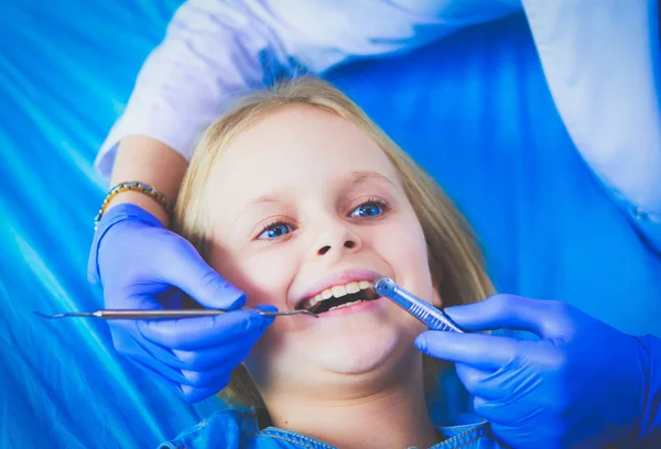 Küçük kız dişçi ofisinde oturuyor..