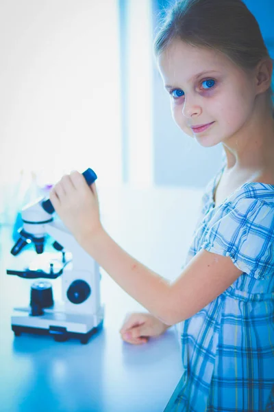 Colegiala mirando a través del microscopio en la clase de ciencias . — Foto de Stock