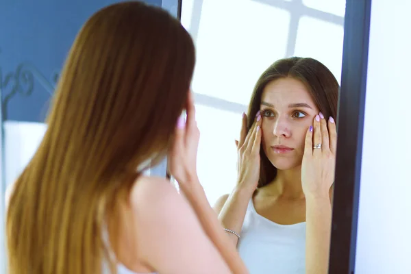 Mladá žena hledá sama odraz v zrcadle doma — Stock fotografie