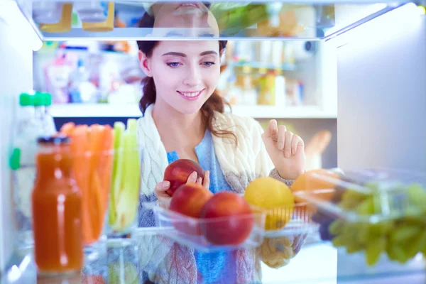 Retrato de fêmea em pé perto da geladeira aberta cheia de alimentos saudáveis, legumes e frutas. Retrato de fêmea — Fotografia de Stock