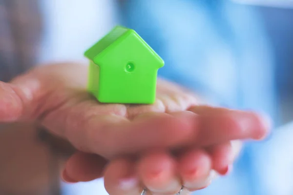 Casa modello in mano a una coppia, in piedi in una nuova casa. Modello di casa . — Foto Stock