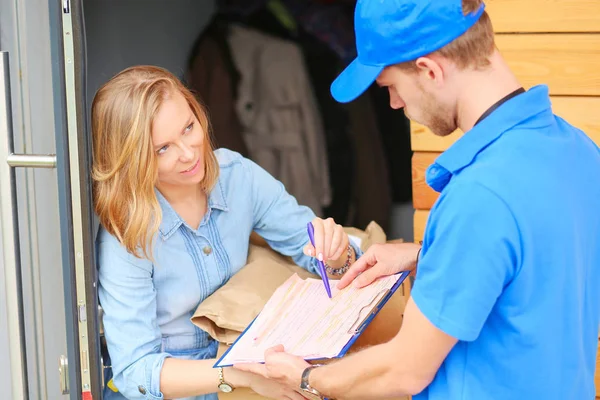 Repartidor sonriente con uniforme azul que entrega la caja de paquetes al destinatario: concepto de servicio de mensajería. Repartidor sonriente en uniforme azul — Foto de Stock