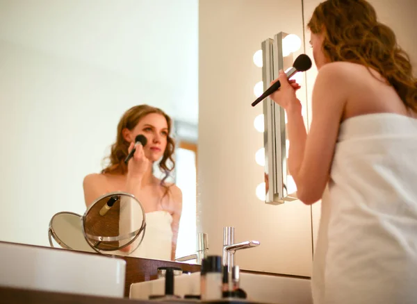 Jeune femme regardant dans le miroir et se maquillant. — Photo