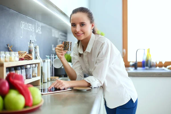 Porträtt av ung kvinna som står mot kök bakgrund. — Stockfoto