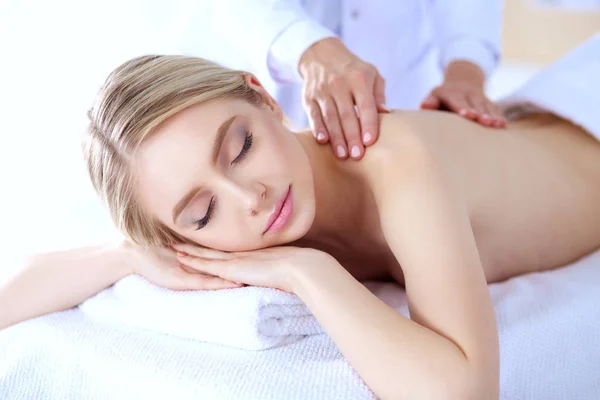 Mujer joven acostada en una mesa de masaje, relajándose con los ojos cerrados. Una mujer. Salón de spa —  Fotos de Stock