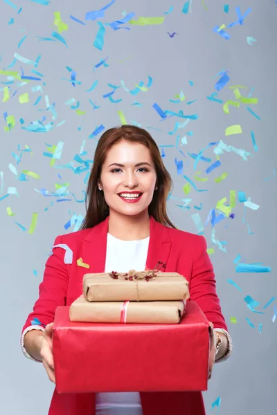 Beautiful happy woman with gift box at celebration party with confetti . Birthday or New Year eve celebrating concept