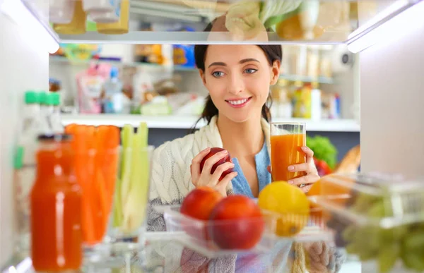 Retrato de fêmea em pé perto da geladeira aberta cheia de alimentos saudáveis, legumes e frutas. Retrato de fêmea — Fotografia de Stock