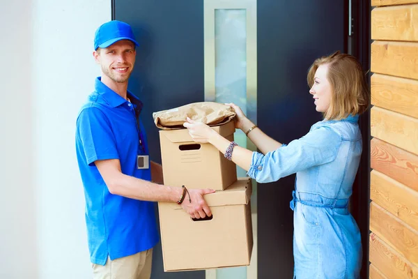 Leende leverans man i blå uniform leverera paket låda till mottagaren - kurir service koncept. Leende leverans man i blå uniform — Stockfoto