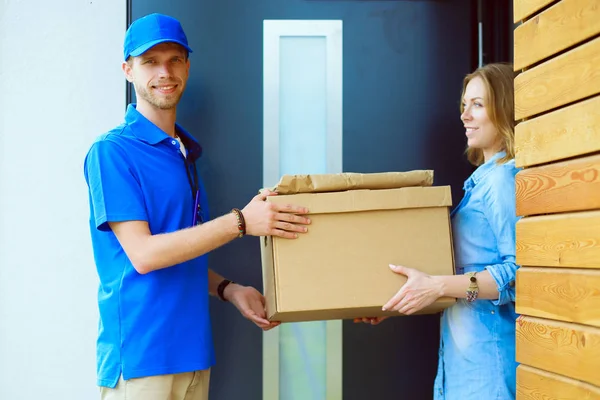Livreur souriant en uniforme bleu livrant la boîte de colis au destinataire concept de service de messagerie. Livreur souriant en uniforme bleu — Photo