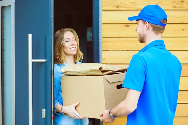 Leende leverans man i blå uniform leverera paket låda till mottagaren - kurir service koncept. Leende leverans man i blå uniform — Stockfoto