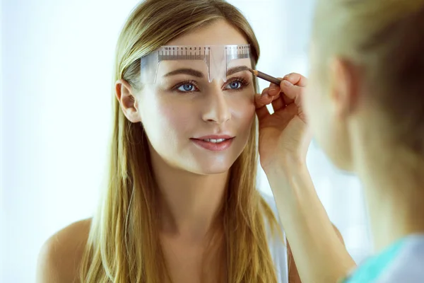 Permanent makeup för ögonbryn. Närbild av vacker kvinna med tjocka bryn i skönhetssalong. — Stockfoto
