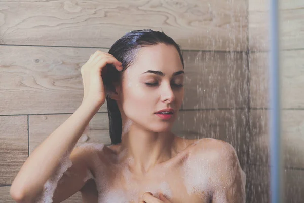 Junge schöne Frau unter der Dusche im Badezimmer. — Stockfoto