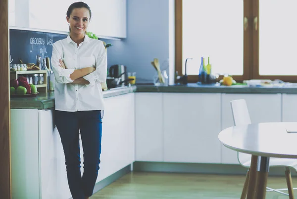 Retrato de mujer joven de pie con los brazos cruzados sobre el fondo de la cocina. Mujer en la cocina . —  Fotos de Stock