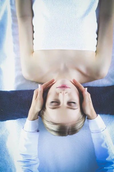 Молода жінка лежить на масажному столі, розслабляючись із закритими очима. Жінка. СПА салон — стокове фото