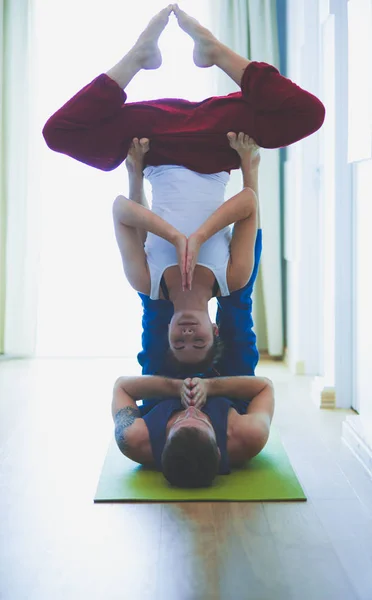 Young healthy couple in yoga position on white background