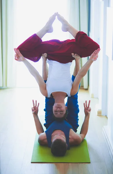 Young healthy couple in yoga position on white background