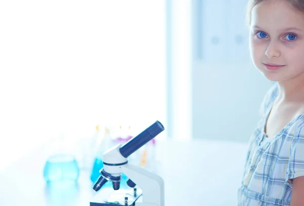 Colegiala mirando a través del microscopio en la clase de ciencias . — Foto de Stock