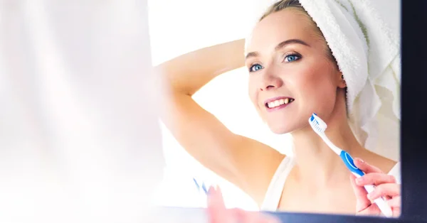 Mladá žena hledá v zrcadle po čištění zubů — Stock fotografie