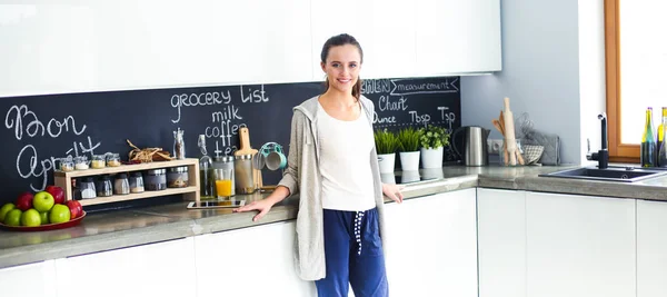 Mujer joven con jugo de naranja y tableta en la cocina. — Foto de Stock