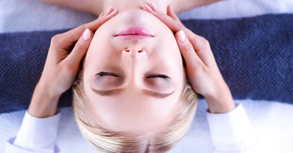 Mujer joven acostada en una mesa de masaje, relajándose con los ojos cerrados. Una mujer. Salón de spa —  Fotos de Stock