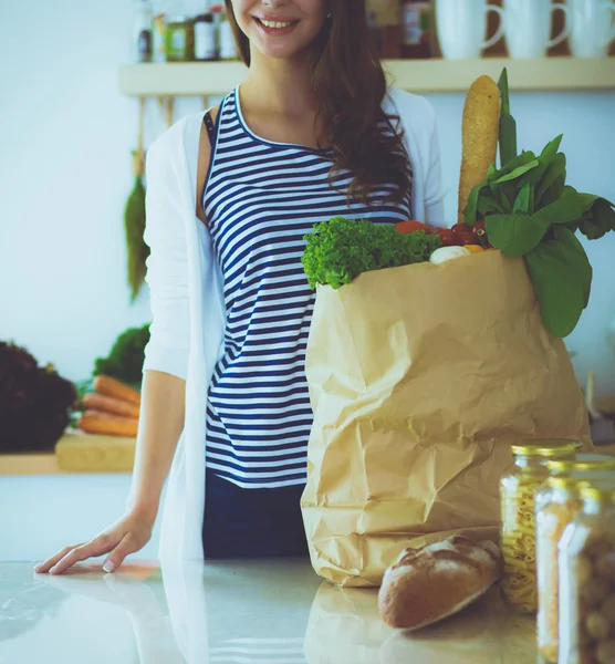 Jonge vrouw met grocery shopping bag met groenten. Permanent in de keuken. Jonge vrouw — Stockfoto