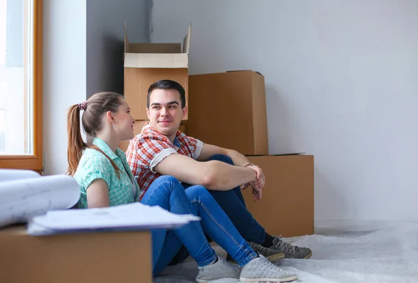 Couple moving in house sitting on the floor. Couple