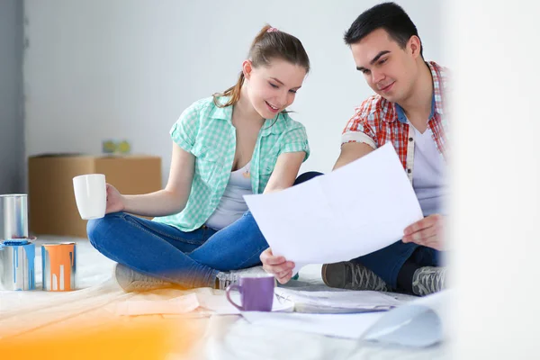 Pareja joven sentada en el suelo y calculando sobre sus ahorros. Pareja joven —  Fotos de Stock