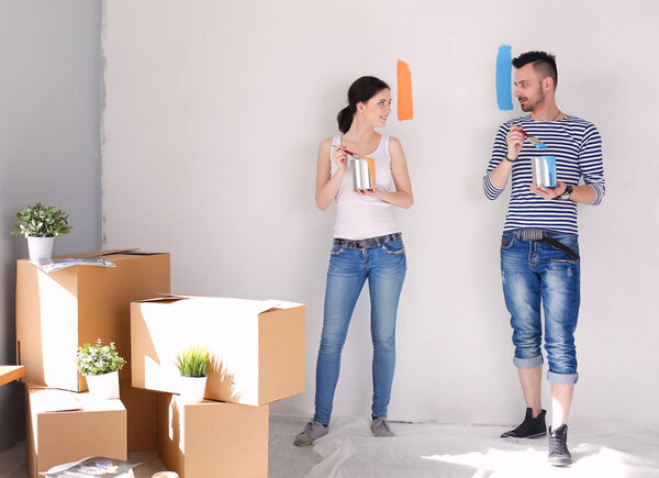 Portrait of happy smiling young couple painting interior wall of new house. young couple
