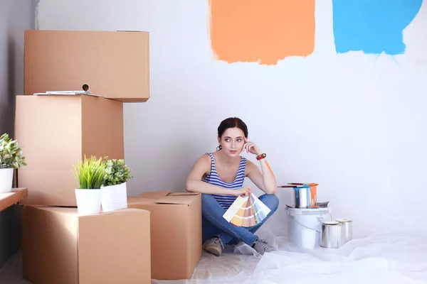 Vrouw kiezen verf kleur vanaf staal voor het nieuwe huis zittend op de houten vloer. Vrouw in huis — Stockfoto