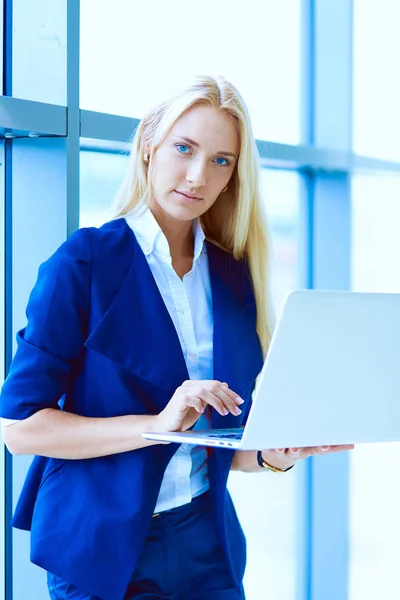 Kobieta stojąc przed office okno trzyma laptopa. Kobieta interesu — Zdjęcie stockowe