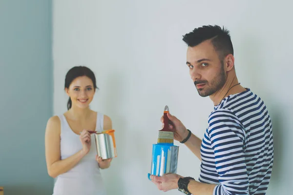 Porträt eines glücklich lächelnden jungen Paares, das die Innenwand des neuen Hauses bemalt. junges Paar — Stockfoto