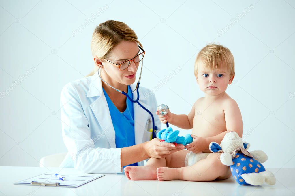 Female doctor is listening kid with a stethoscope in clinic