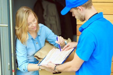 Mavi üniformalı gülümseyen kurye servis konseptine paket kutusu teslim eden teslimatçı. Mavi üniformalı gülümseyen teslimatçı.