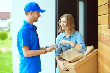 Mavi üniformalı gülümseyen kurye servis konseptine paket kutusu teslim eden teslimatçı. Mavi üniformalı gülümseyen teslimatçı.