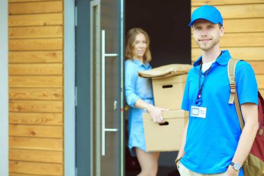 Mavi üniformalı gülümseyen kurye servis konseptine paket kutusu teslim eden teslimatçı. Mavi üniformalı gülümseyen teslimatçı.