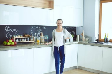 Mutfakta portakal suyu ve tableti olan genç bir kadın..