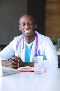 Masada dizüstü bilgisayarla çalışan genç bir Afrikalı doktor. Doktor bey. İşyeri