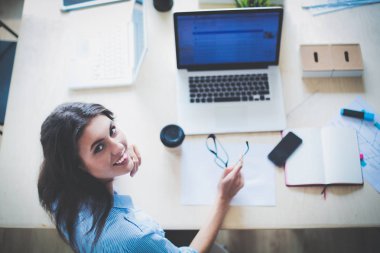 Ofis masasında oturan genç bir kadın dizüstü bilgisayar ekranına bakıyor. Genç kadın.