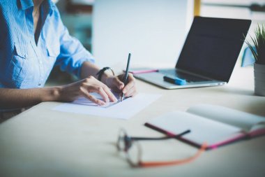 Ofis masasında dizüstü bilgisayarla oturan genç bir kadın. Genç bir kadın. Dizüstü bilgisayar