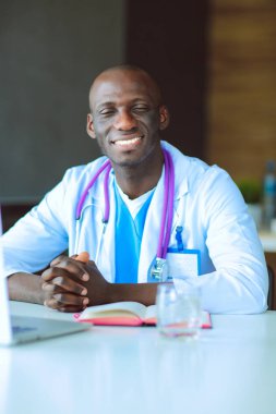 Masada dizüstü bilgisayarla çalışan genç bir Afrikalı doktor. Doktor bey. İşyeri