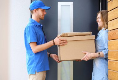 Mavi üniformalı gülümseyen kurye servis konseptine paket kutusu teslim eden teslimatçı. Mavi üniformalı gülümseyen teslimatçı.