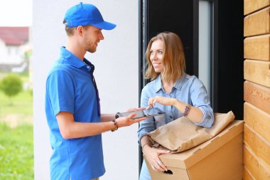 Mavi üniformalı gülümseyen kurye servis konseptine paket kutusu teslim eden teslimatçı. Mavi üniformalı gülümseyen teslimatçı.