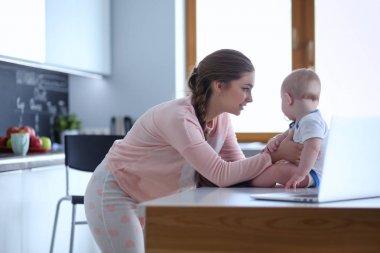 Annesi bebeğini evde parlak mutfakta ile.
